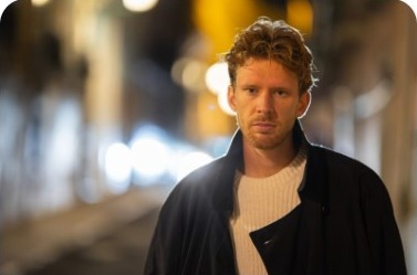 Actor standing on a city street at night