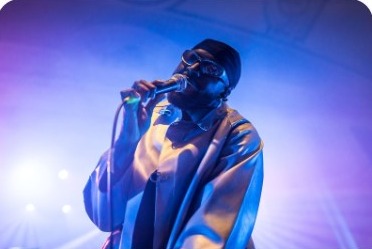 Singer performing on stage under purple lights